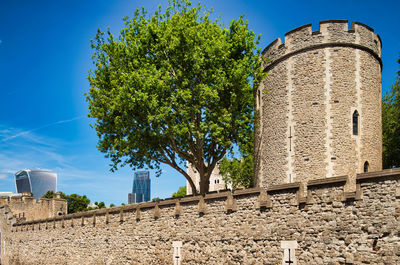 Low angle view of castle and trees against blue sky