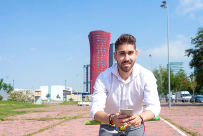 Outdoor portrait of handsome young man with mobile phone and fixed gear bicycle in the street.