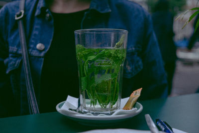 Close-up of drink in glass on table by woman