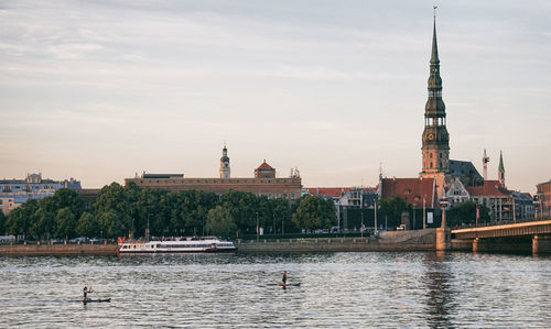 View of buildings by river against sky