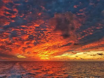 Scenic view of sea against cloudy sky during sunset