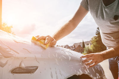 Midsection of man holding ice while standing by car