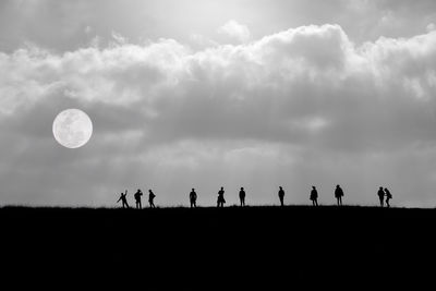 Silhouette people on field against sky