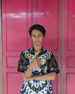 Portrait of smiling young man standing against wall