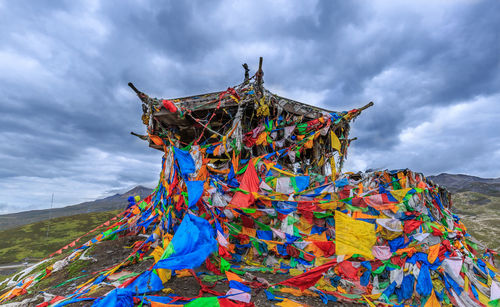 Colorful bunting flags on structure against cloudy sky