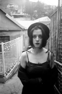 Portrait of young woman standing by railing