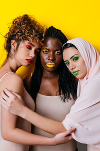 Portrait of women sitting against yellow background