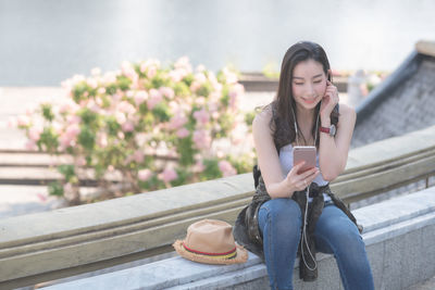 Young woman using mobile phone while sitting on camera