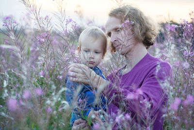 Rear view of people against purple flowering plants
