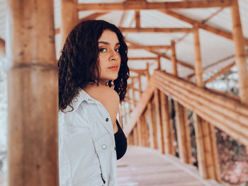 Portrait of young woman standing against railing