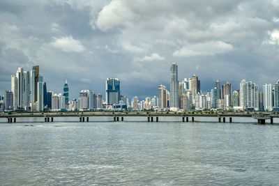 Sea by modern buildings against sky in city