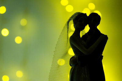 Close-up of couple figurine against illuminated light