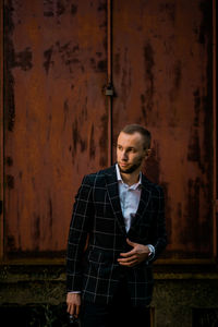 Portrait of young man standing against wall