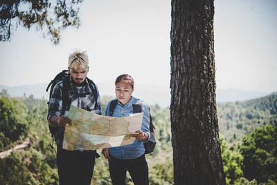 Man and woman reading map at forest