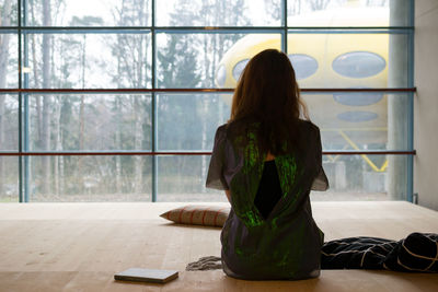 Rear view of woman sitting on wooden flooring