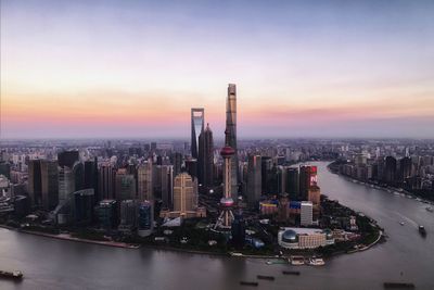 Aerial view of river amidst buildings against sky during sunset