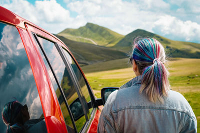 Rear view of young woman standing against mountain