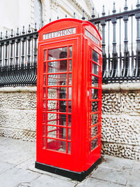 Red telephone booth on sidewalk