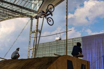 Low angle view of man cycling against sky in city