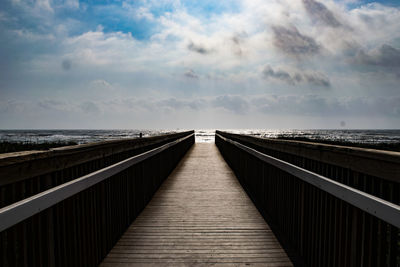 Footbridge over sea against sky