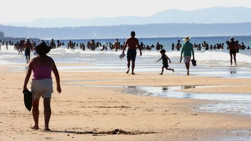 People on shore at beach against sky