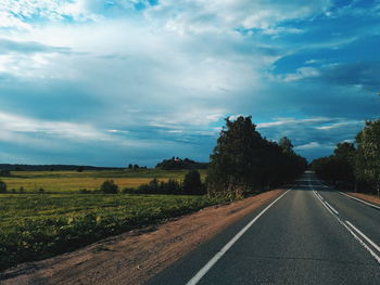 Road by trees against sky