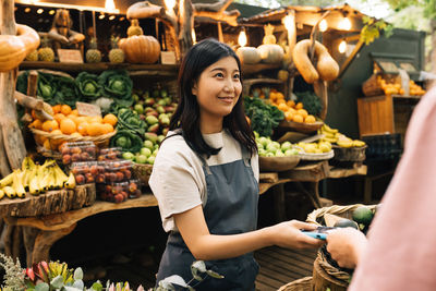 Portrait of smiling woman holding fruits at market