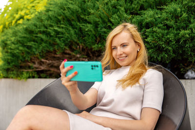 Young blond woman making selfie on smartphone for her followers. young influencer girl. 