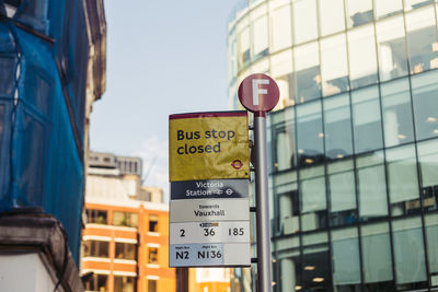 Low angle view of road sign by building in city