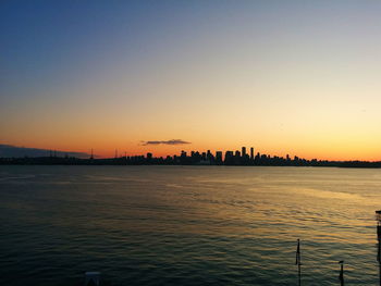 Scenic view of silhouette city against clear sky during sunset