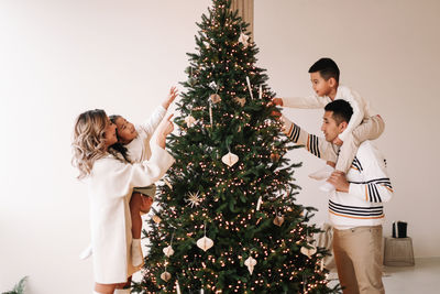 An asian multi-racial family with two children celebrate the christmas holiday in a decorated indoor