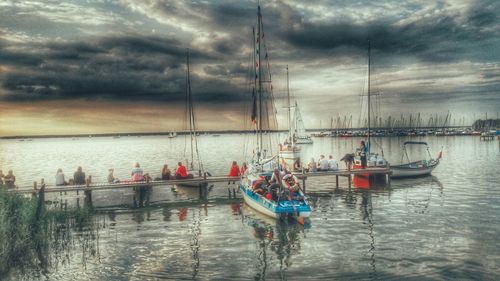 Boats in sea against cloudy sky