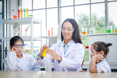 Smiling teacher showing experiment to students in laboratory