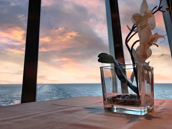 Close-up of table by sea against sky during sunset