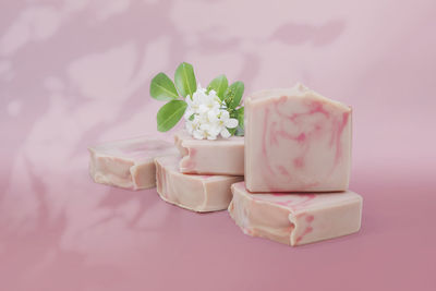 Close-up of pink rose on table against white background