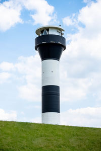 Low angle view of lighthouse on field against sky