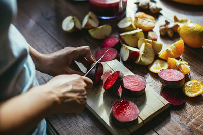 High angle view of hand holding fruits on cutting board