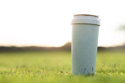 Close-up of beer glass on field against clear sky