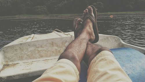 Low section of man relaxing on boat in lake