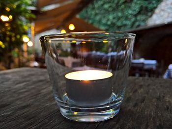 Close-up of burning tea light in glass on table at back yard