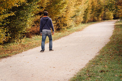 Rear view of man walking on footpath amidst trees