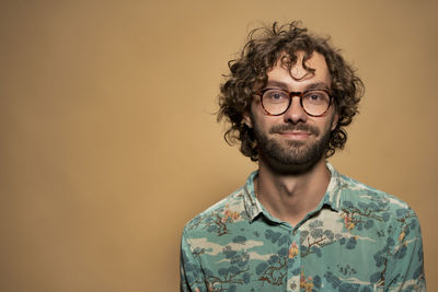 Portrait of young man with curly hair against yellow background