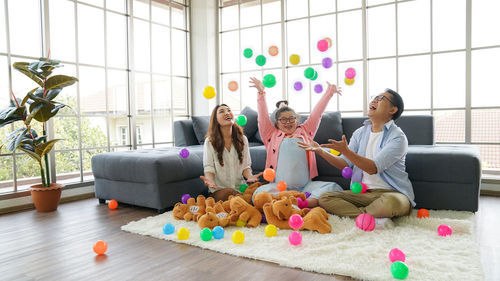 Full length of people sitting by toys on floor