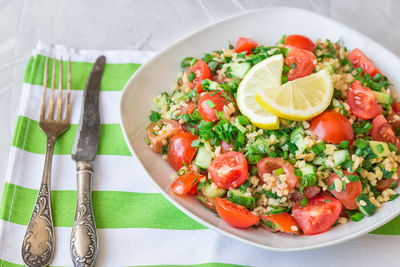 Tabbouleh salad on a dish on light gray concrete background. healthy vegetarian food.