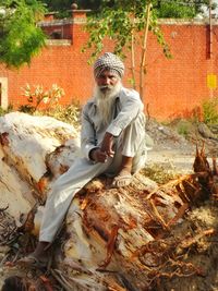 Portrait of senior man sitting on fallen tree trunk