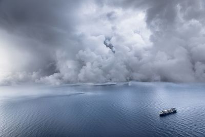 Aerial view of boat on sea against cloudy sky