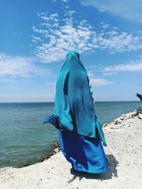 Rear view of woman on beach against blue sky