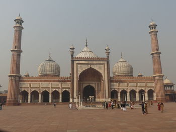 Group of people in front of historic building against clear sky