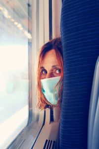 Portrait of young woman looking through window