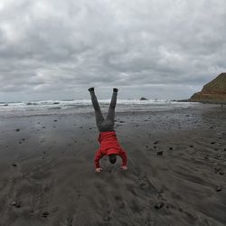Upside down image of man on beach against sky